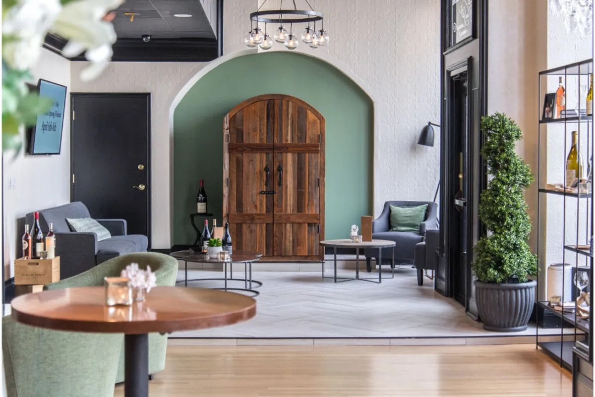A cozy nook within the lounge featuring a wooden door, a green accent wall, comfortable seating, and a display shelf. The setting is intimate, ideal for wine tastings, relaxed celebrations, and engaging discussions, reinforcing a sense of exclusivity and privacy.