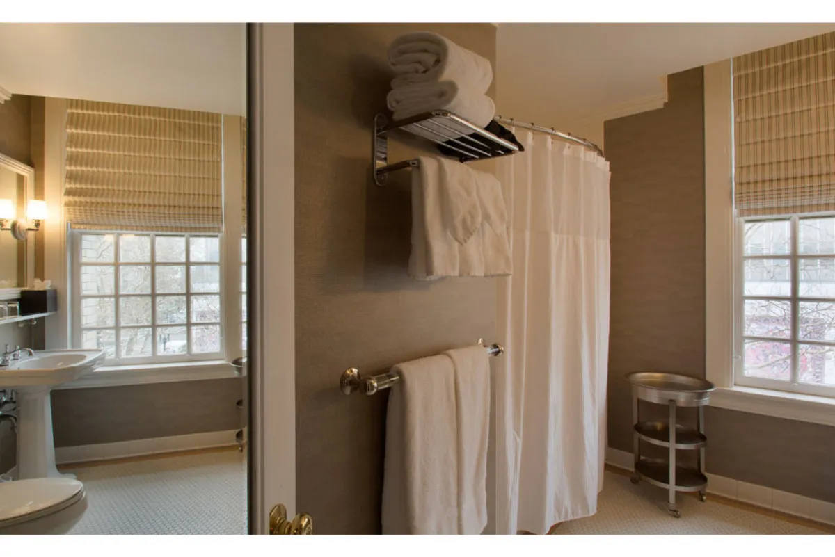 A tranquil bathroom view featuring a shower curtain, soft towels, and a window that invites natural light. The space offers a sense of privacy and self-care.